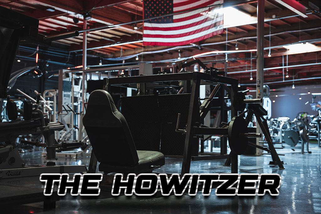 The Howitzer plate-loaded machine under the red lights of the gym