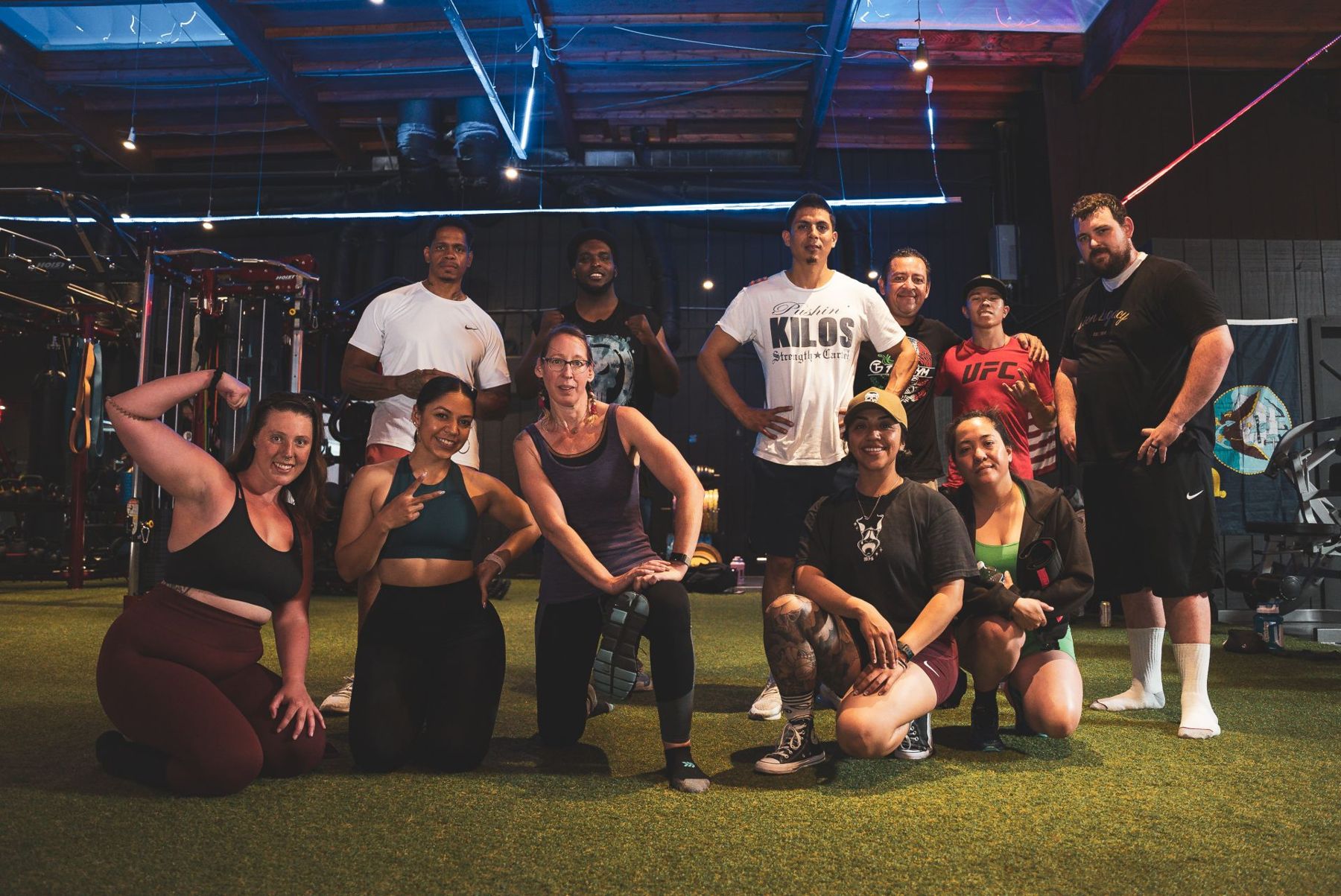 A group of people posing on the turf at War House Gym