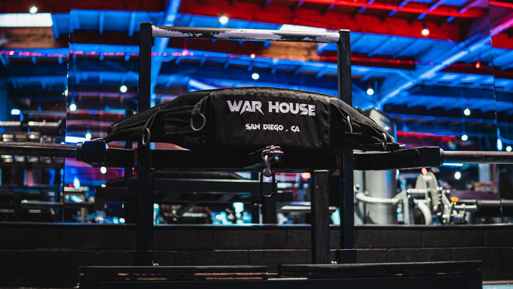 A black War House sandbag resting on a rack under red and blue light