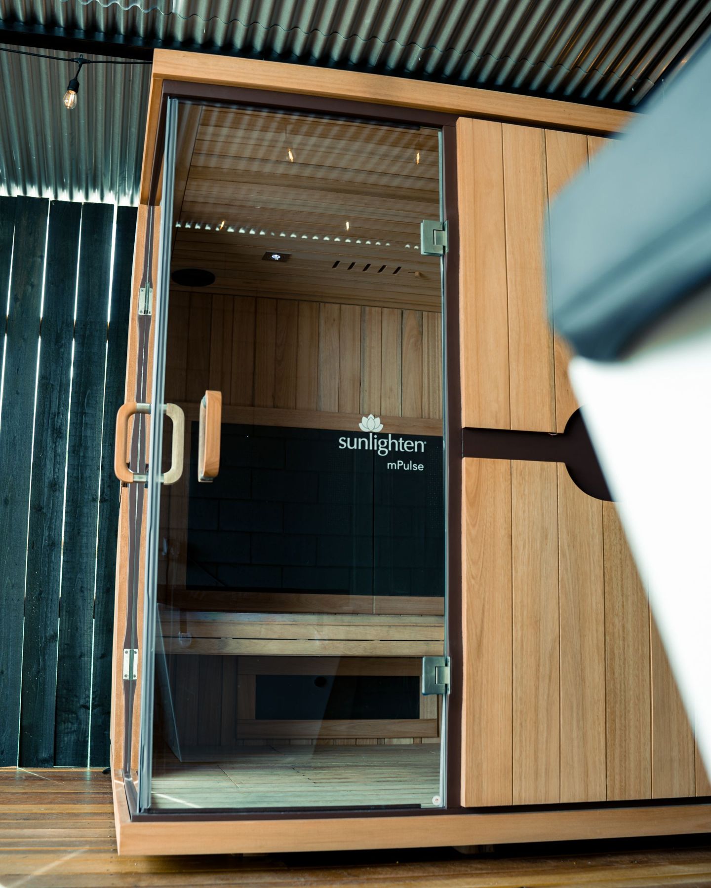 A cedar sauna cabin on the wellness patio with a glass door